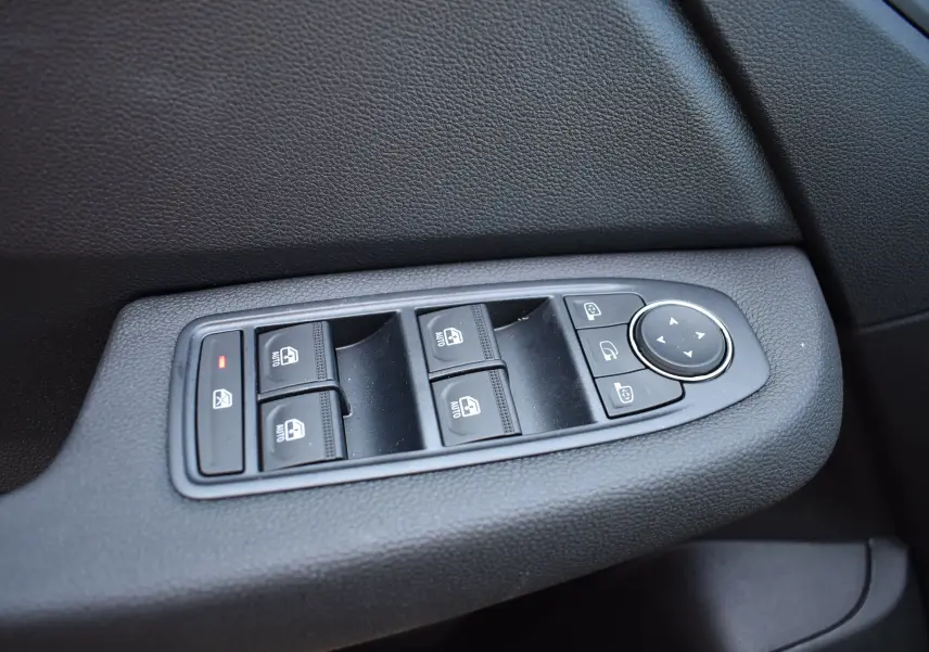Gros plan sur les commandes de lève-vitres et rétroviseurs côté conducteur d’une Renault Clio V noire, 2025.