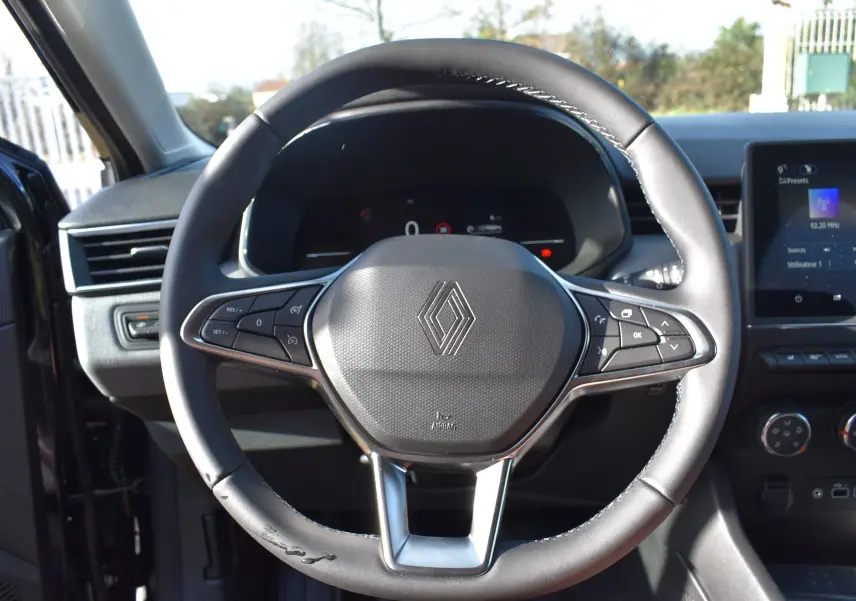 Vue centrée sur le volant noir de la Renault Clio V 2025 avec commandes intégrées et tableau de bord numérique.