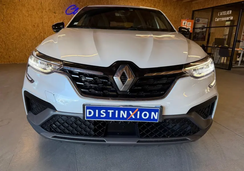 Renault Arkana blanc nacré en 3/4 avant droit, avec jantes noires et calandre noire brillante.