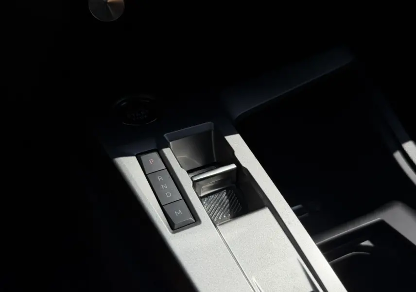 Gros plan sur la console centrale grise de la Peugeot 308 Hybrid 145, avec sélecteur de boîte auto et bouton start/stop.