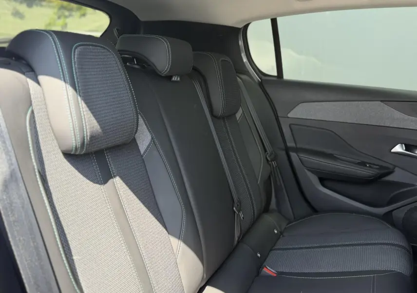 Vue latérale droite des sièges arrière en tissu et TEP noir avec surpiqûres bleues du Peugeot 308 Hybrid 145 Allure 2025.