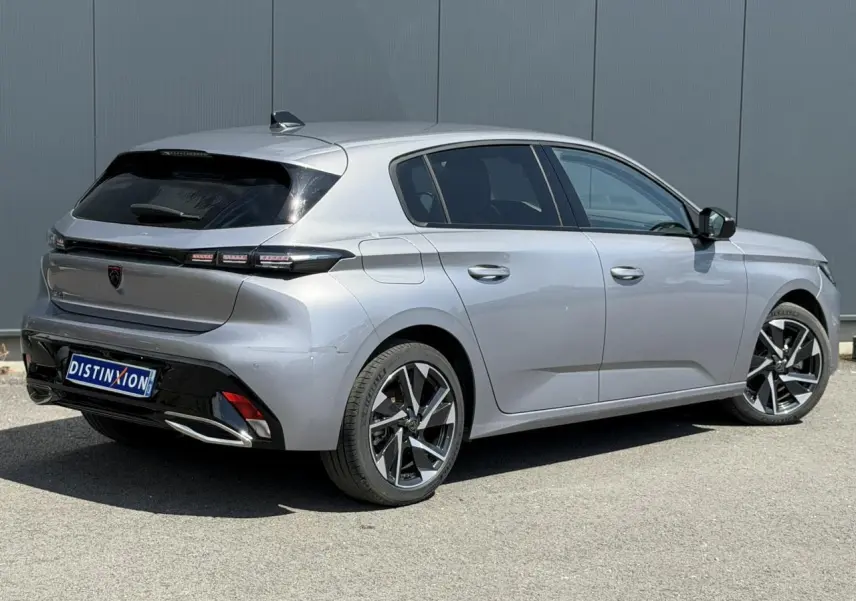 Vue 3/4 arrière droite d'une Peugeot 308 Hybrid 145 gris Artense avec jantes alliage 17'' et feux LED distinctifs.