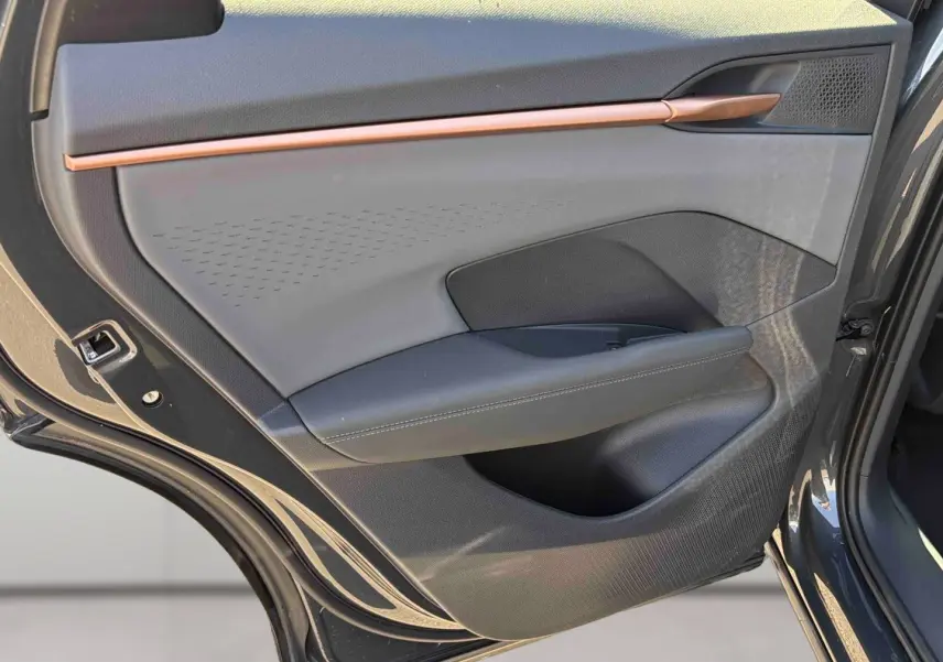Gros plan sur la porte arrière droite grise du CUPRA TERRAMAR 2025 avec insert décoratif cuivre et accoudoir en cuir noir.