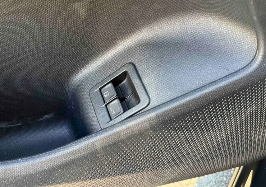 Gros plan sur les boutons d'ouverture de la trappe à carburant et du coffre sur la porte intérieure noire du CUPRA TERRAMAR.