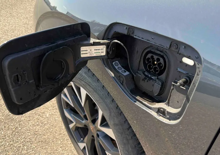 Prise de recharge ouverte sur le côté gauche d’une CUPRA TERRAMAR grise, avec jante anthracite visible.