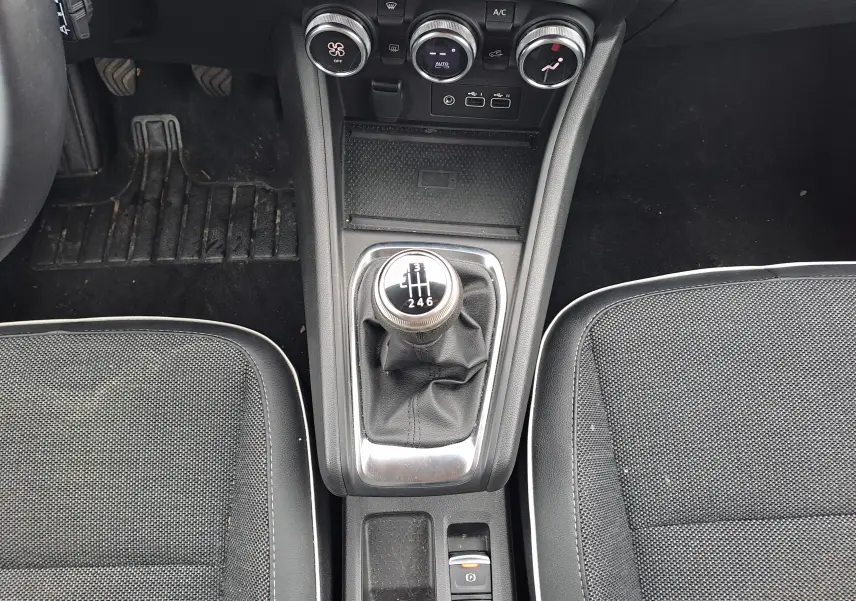 Vue plongeante sur la console centrale du Renault Captur 2024, mettant en valeur la boîte manuelle et les sièges noirs.