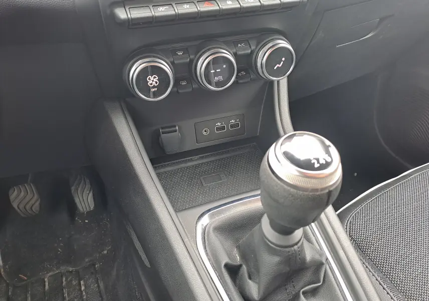 Gros plan sur la console centrale intérieure du Renault Captur 2024, mettant en valeur le levier de vitesses manuel et les commandes de climatisation.