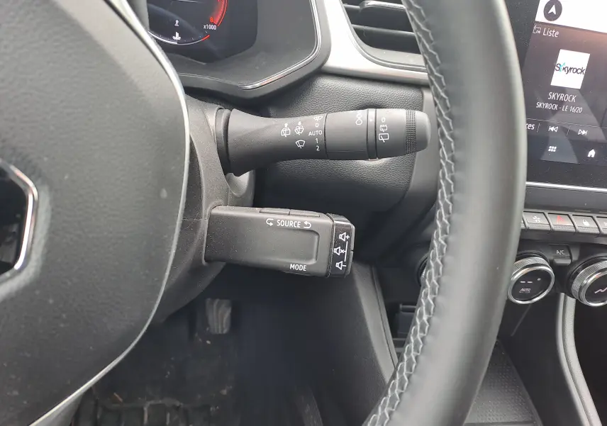 Gros plan sur la colonne de direction et commandes au volant du Renault Captur 2024, intérieur noir avec détails fonctionnels visibles.