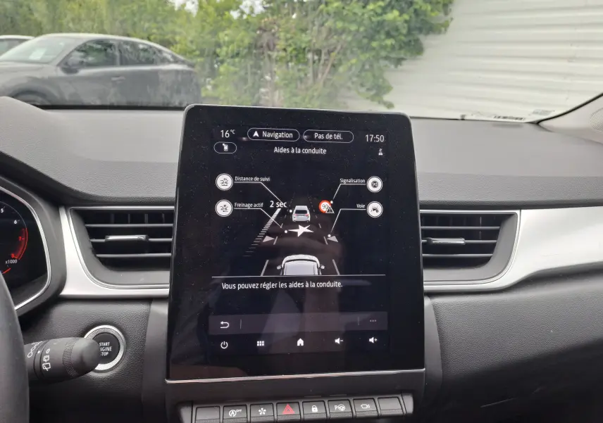 Vue intérieure du tableau de bord du Renault Captur 2024, écran tactile central affichant les aides à la conduite.