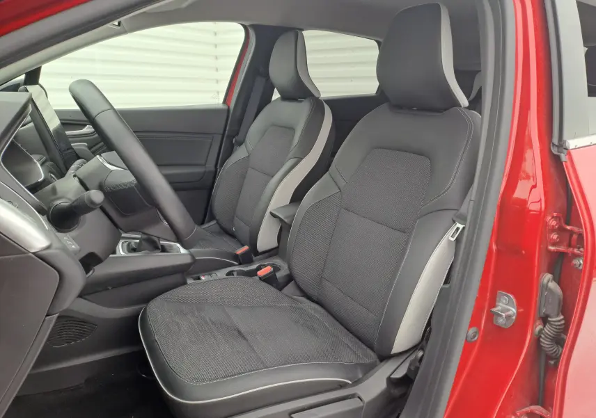 Vue intérieure côté conducteur du Renault Captur rouge flamme métal 2024, sièges bi-matière noir et gris clair.