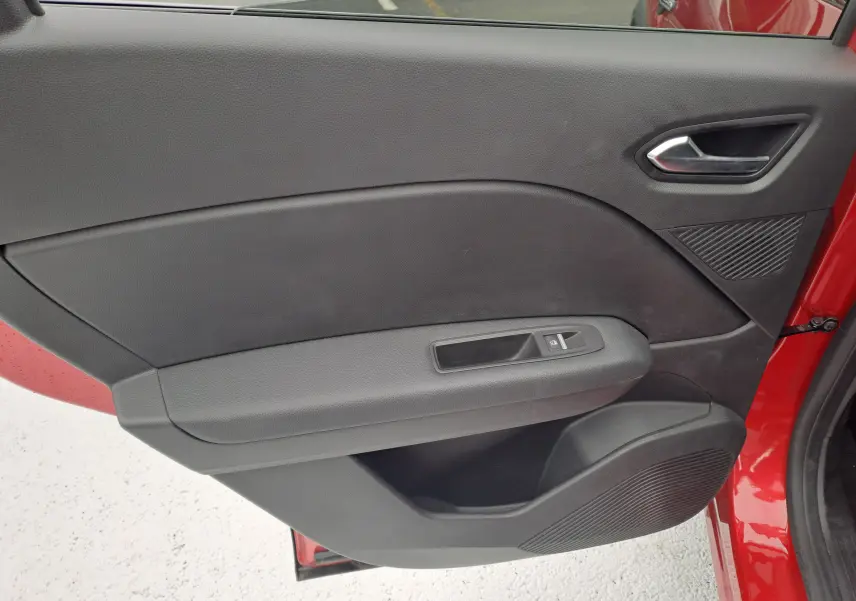 Vue rapprochée de la porte arrière droite noire avec poignée et commande de vitre du Renault Captur rouge flamme 2024.