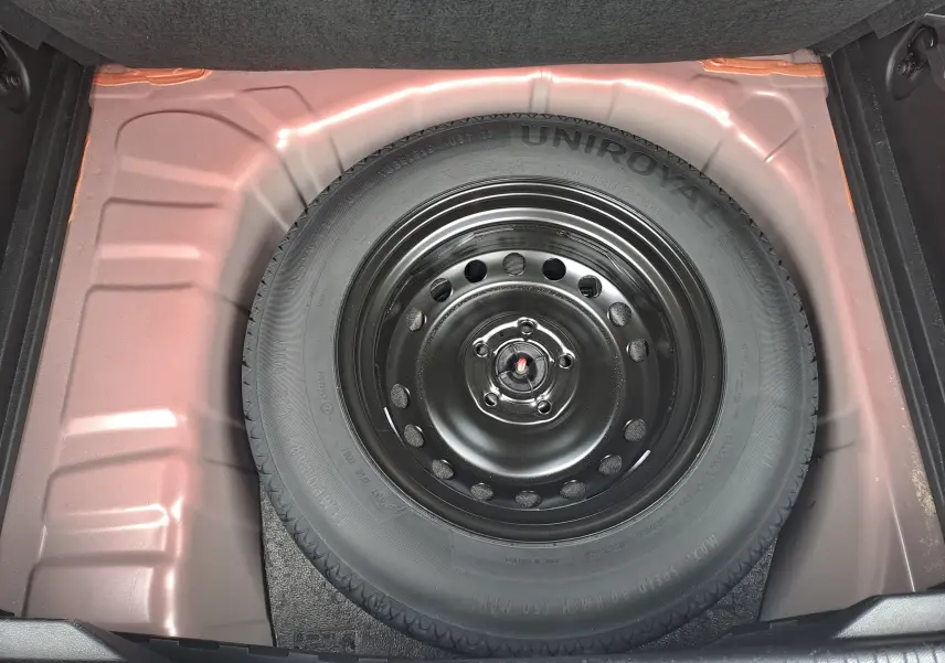 Vue plongeante sur la roue de secours noire dans le coffre rouge flamme métal du Renault Captur TCE 90CH TECHNO 2024.