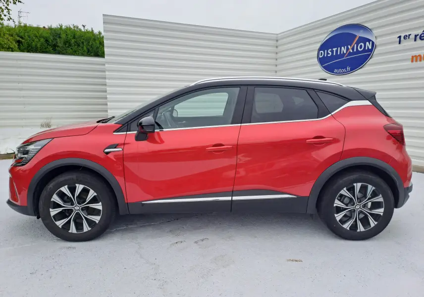 Profil côté gauche d'un Renault Captur 2024 rouge flamme métal avec toit noir et jantes alliage bicolores.