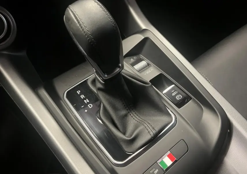 Le levier de vitesse automatique cuir noir de l'Alfa Romeo Tonale 2024 avec badge tricolore italien sur console centrale.