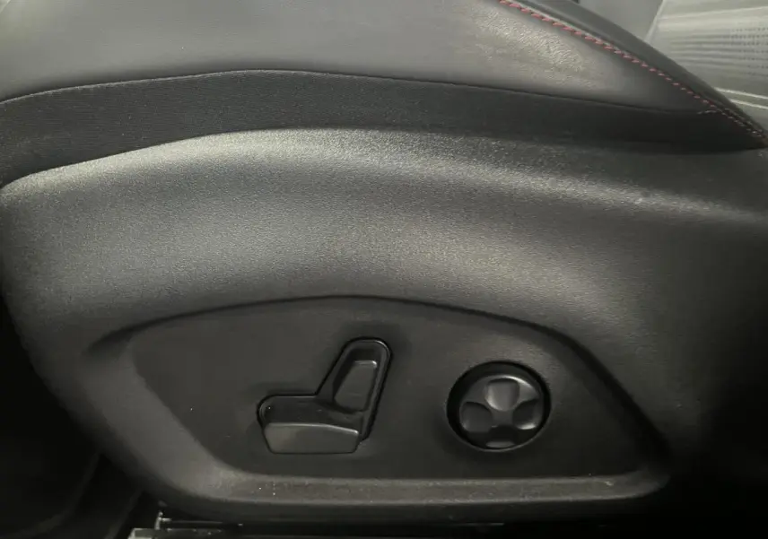 Gros plan sur les commandes électriques du siège conducteur en cuir noir avec surpiqûres rouges de l'Alfa Romeo Tonale 2024.