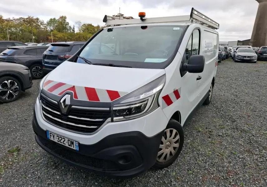 Renault Trafic Fourgon blanc en 3/4 avant droit avec bandes rouges réfléchissantes et galerie sur le toit.