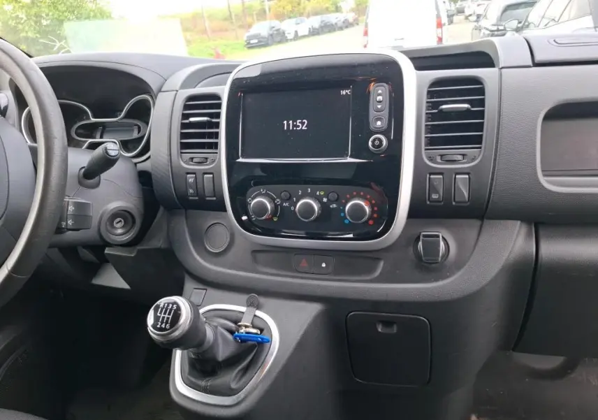 Vue intérieure du tableau de bord du Renault Trafic Fourgon blanc 2021, avec écran central, commandes de climatisation et levier de vitesse manuel.