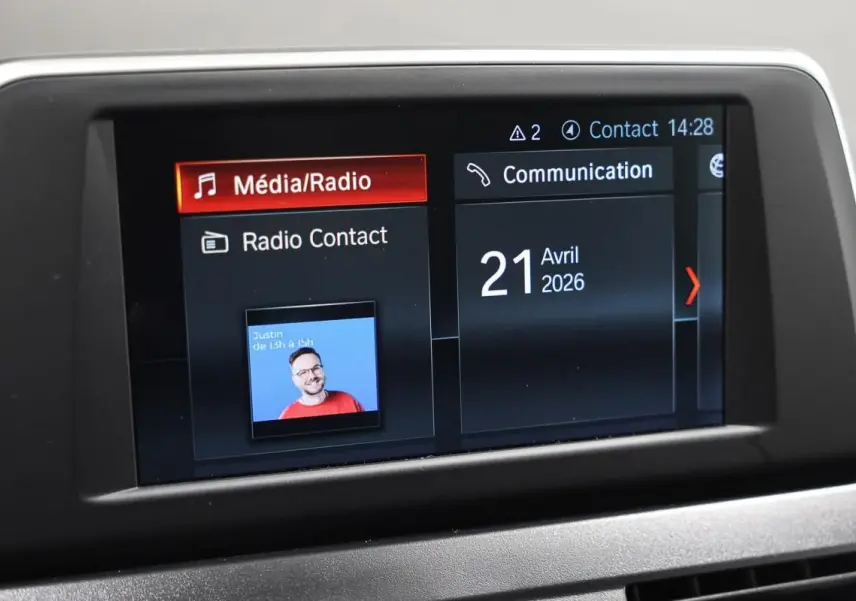 Écran central de la BMW Série 2 Active Tourer 216d blanc affichant les menus Média/Radio et Communication avec date du 21 avril 2026.