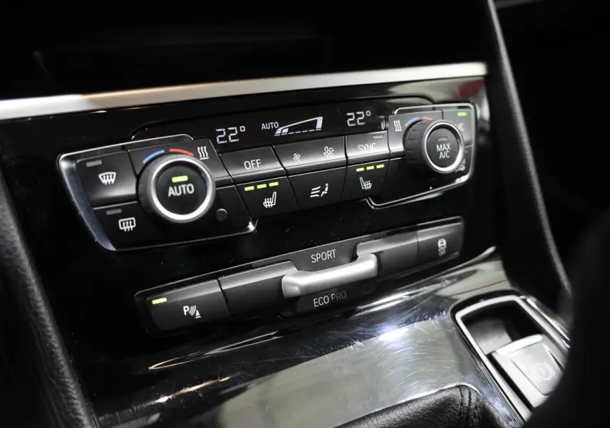 Vue rapprochée de la console centrale de la BMW Série 2 Active Tourer 216d, avec commandes de climatisation et modes de conduite.