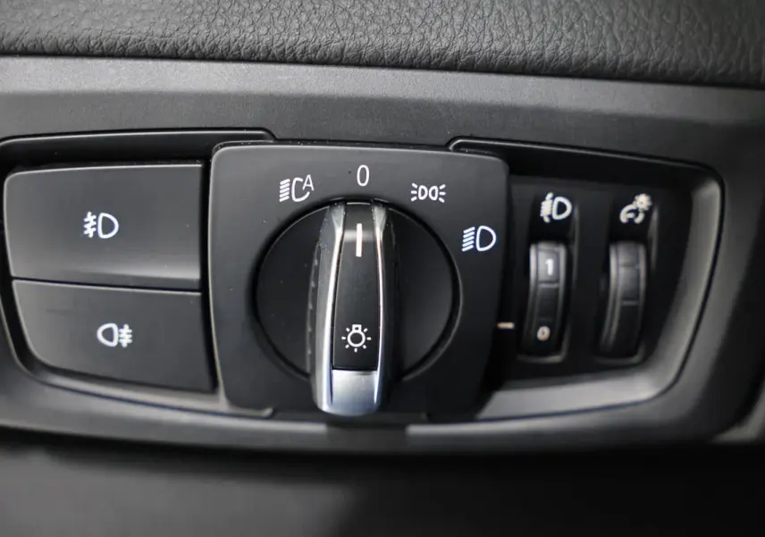 Gros plan sur la commande des phares et réglages lumineux intérieurs d'une BMW Série 2 Active Tourer blanche.