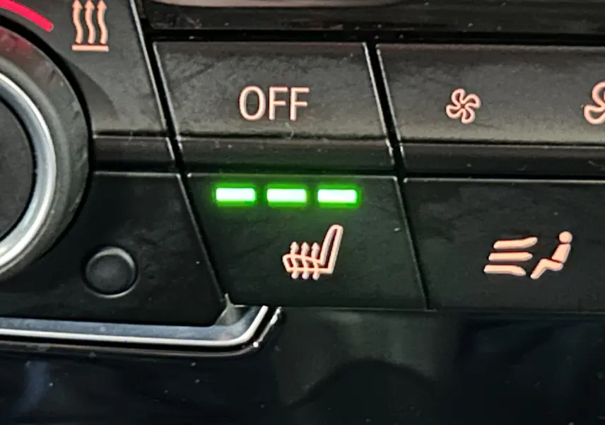 Détail du tableau de bord avec bouton de sièges chauffants activés sur BMW Série 2 Active Tourer blanc.