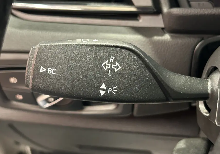 Gros plan sur la commande de clignotant noire dans l'habitacle d'une BMW Série 2 Active Tourer blanche de 2021.
