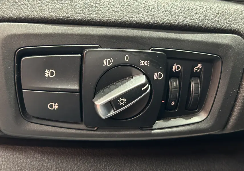 Gros plan sur la commande des phares et réglages d’éclairage intérieur d’une BMW Série 2 Active Tourer blanche.