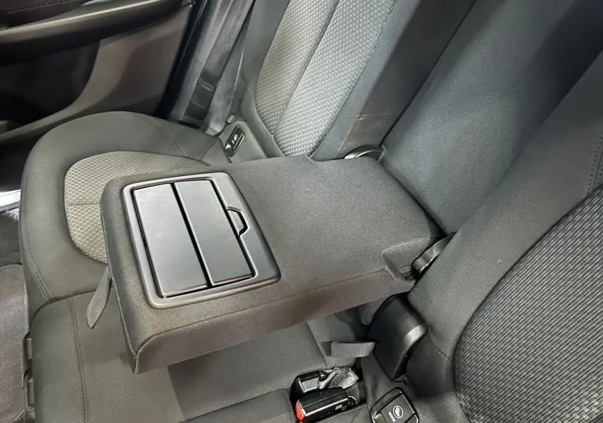 Vue intérieure des sièges arrière noirs d'une BMW Série 2 Active Tourer 216d avec accoudoir central relevé.