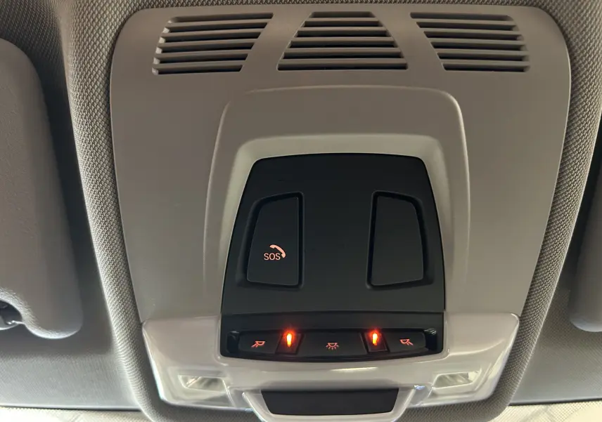 Vue en gros plan du plafonnier intérieur gris avec boutons SOS et éclairage allumé dans une BMW Série 2 Active Tourer 216d blanche.