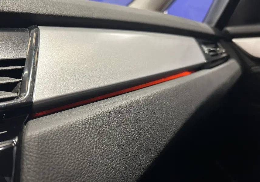 Détail de la planche de bord côté passager de la BMW Série 2 Active Tourer 216d 2021 avec bandeau décoratif rouge et finition noire texturée.