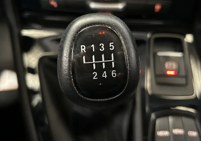 Gros plan sur le levier de vitesses manuel noir de la BMW Série 2 Active Tourer 216d, avec commandes environnantes visibles.