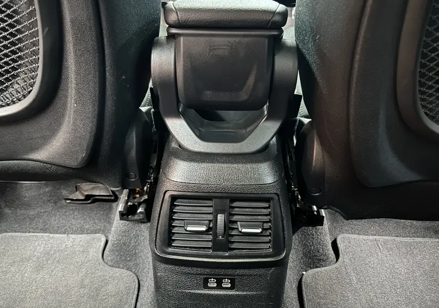 Vue rapprochée de la console centrale arrière noire avec bouches d’aération et ports USB dans une BMW Série 2 Active Tourer blanche.