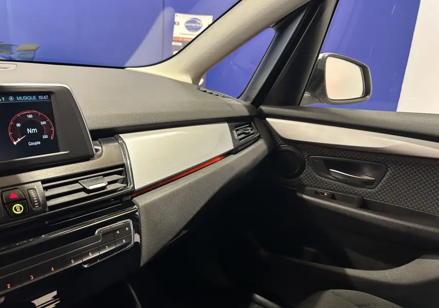 Vue intérieure côté passager de la BMW Série 2 Active Tourer 216d 2021 avec tableau de bord noir et détails argentés.