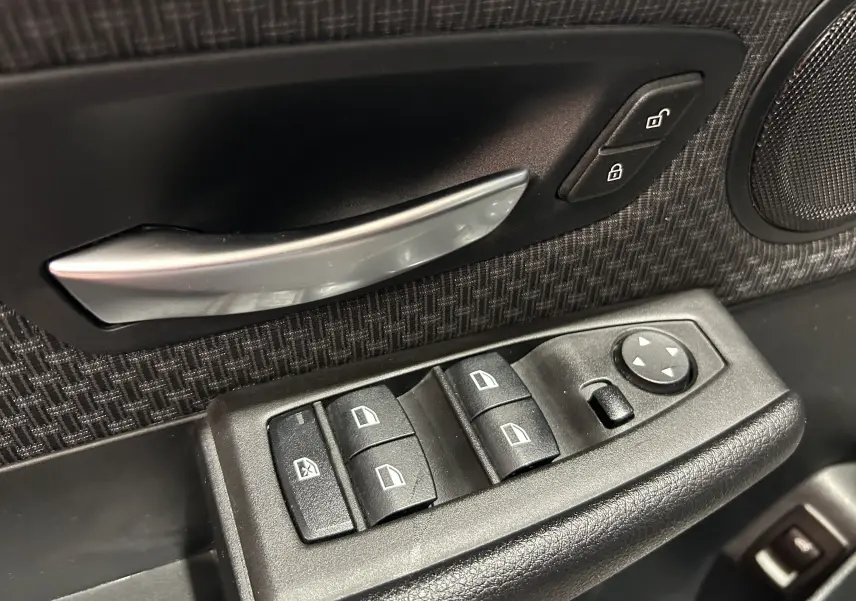 Gros plan sur la commande des vitres et la poignée intérieure côté conducteur d’une BMW Série 2 Active Tourer blanche.