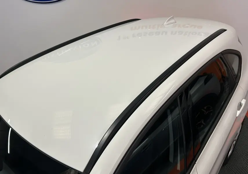 Vue plongeante sur le toit blanc et les montants noirs d'une BMW Série 2 Active Tourer 216d, côté droit.