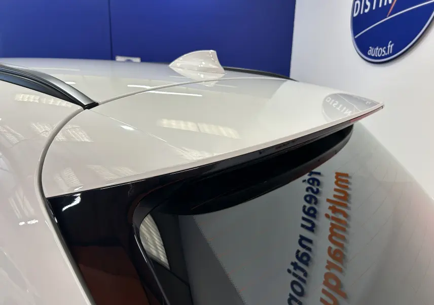 Gros plan sur l’angle arrière droit d’une BMW Série 2 Active Tourer blanche, mettant en valeur l’antenne requin et le becquet.