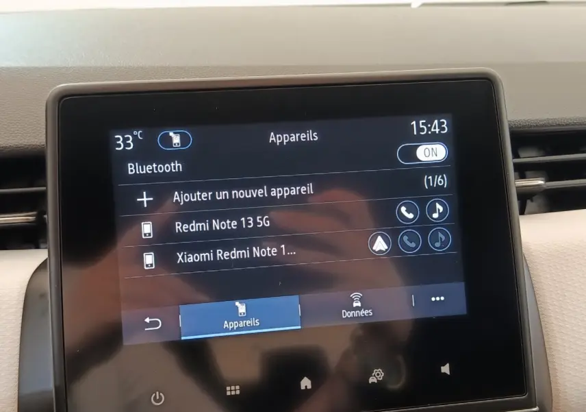 Écran tactile central de la Renault Clio blanc, affichant la connexion Bluetooth avec deux appareils listés.