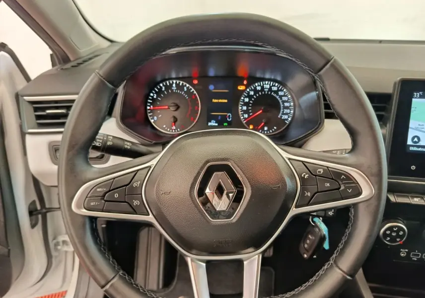 Vue intérieure centrée sur le volant cuir noir de la Renault Clio 2023 avec tableau de bord et écran tactile visible.