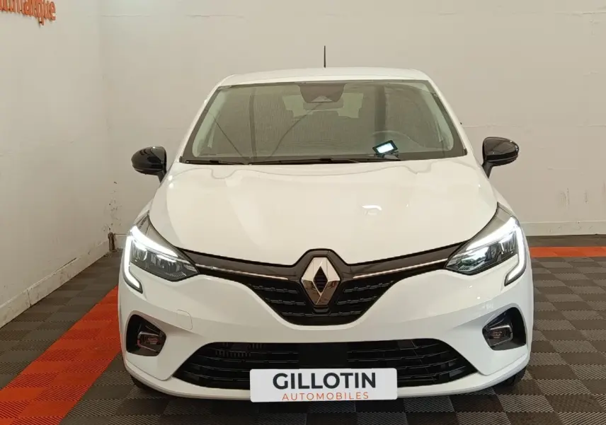 Vue avant d'une Renault Clio blanche 2023 avec feux LED allumés et rétroviseurs noirs contrastants.