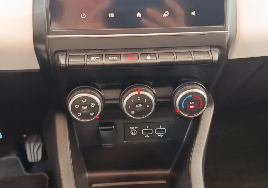 Vue rapprochée du tableau de bord central noir de la Renault Clio blanche 2023 avec commandes climatisation et ports USB.