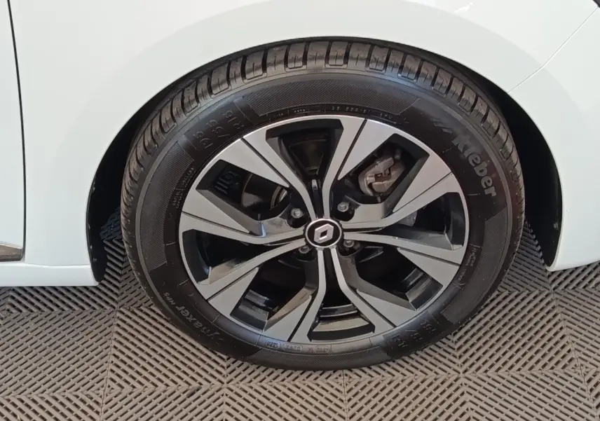 Gros plan sur la roue avant droite de la Renault Clio blanche, mettant en valeur la jante alliage au design moderne.
