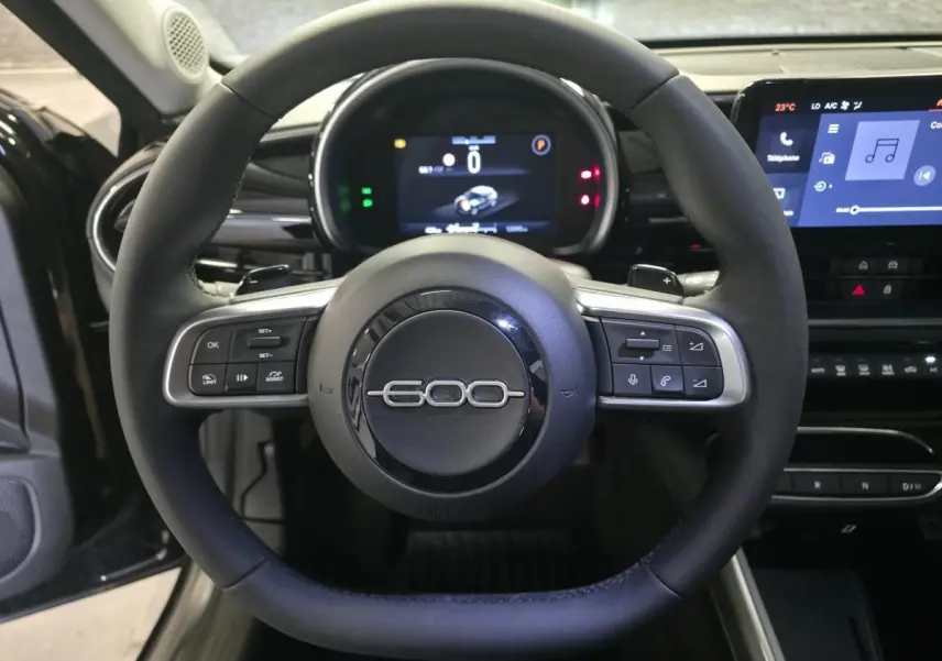 Vue rapprochée du volant noir marqué 600 du tableau de bord numérique et écran tactile du Fiat 600 Hybrid 2025.