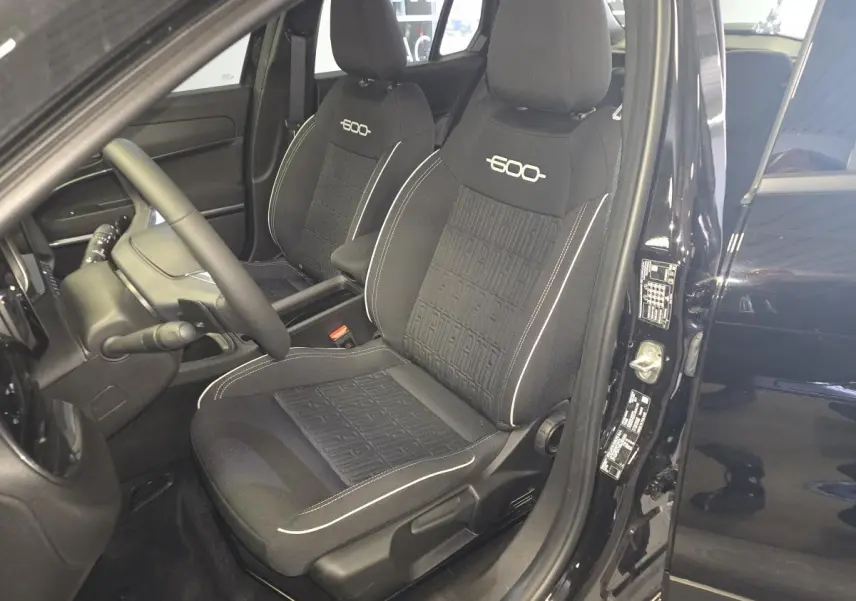 Vue intérieure côté conducteur de la FIAT 600 1.2 Hybrid noire, avec sièges spécifiques brodés et volant Soft-Touch.