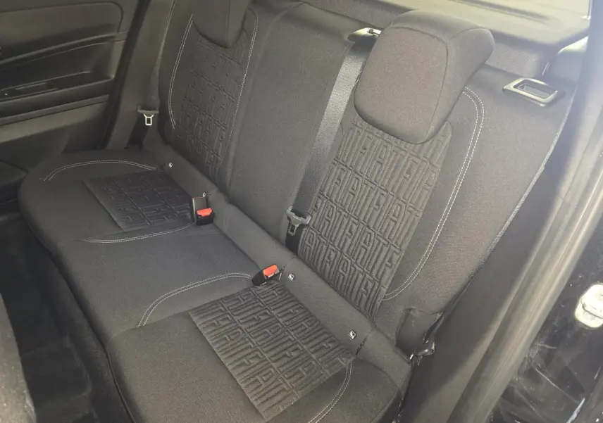 Vue intérieure de la banquette arrière noire du Fiat 600 Hybrid 2025 avec motifs FIAT embossés sur les dossiers.