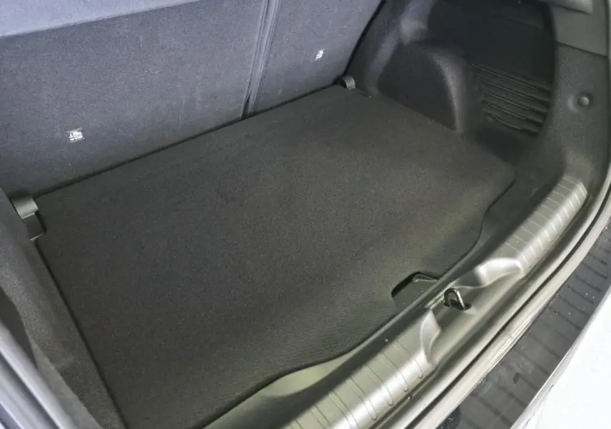 Vue rapprochée du coffre noir du Fiat 600 1.2 Hybrid Icône 2025, montrant le plancher et les finitions intérieures.