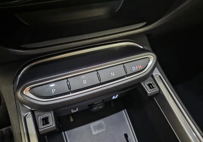 Gros plan sur la console centrale noire du Fiat 600 Hybrid 2025, avec boutons de boîte auto P, R, N, D/M et chargeur induction.