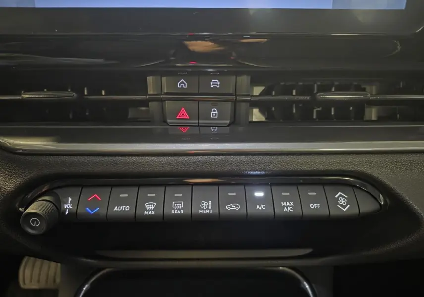 Vue rapprochée du tableau de bord noir de la Fiat 600 Hybrid 2025, montrant les commandes de climatisation et les boutons centraux.