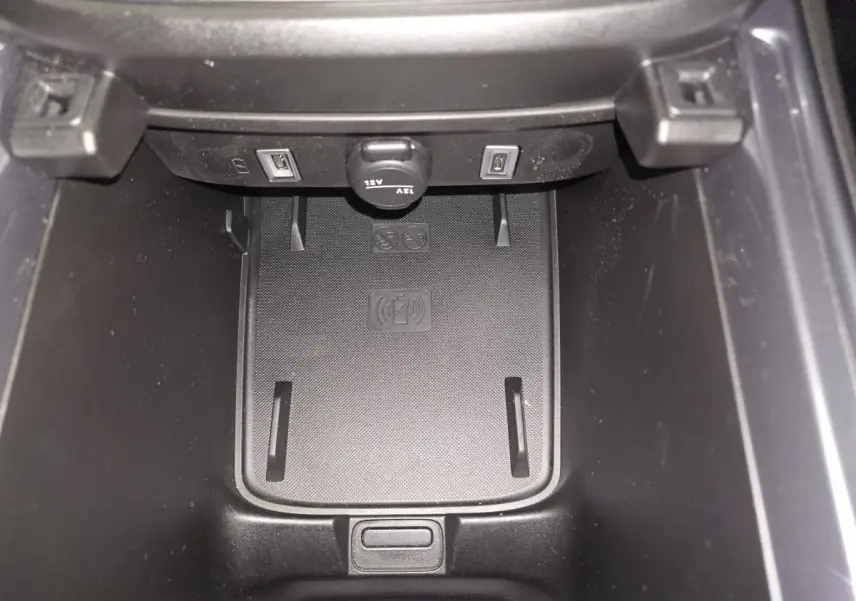 Gros plan sur la console centrale du Fiat 600 noir, montrant le chargeur smartphone par induction et deux ports USB.