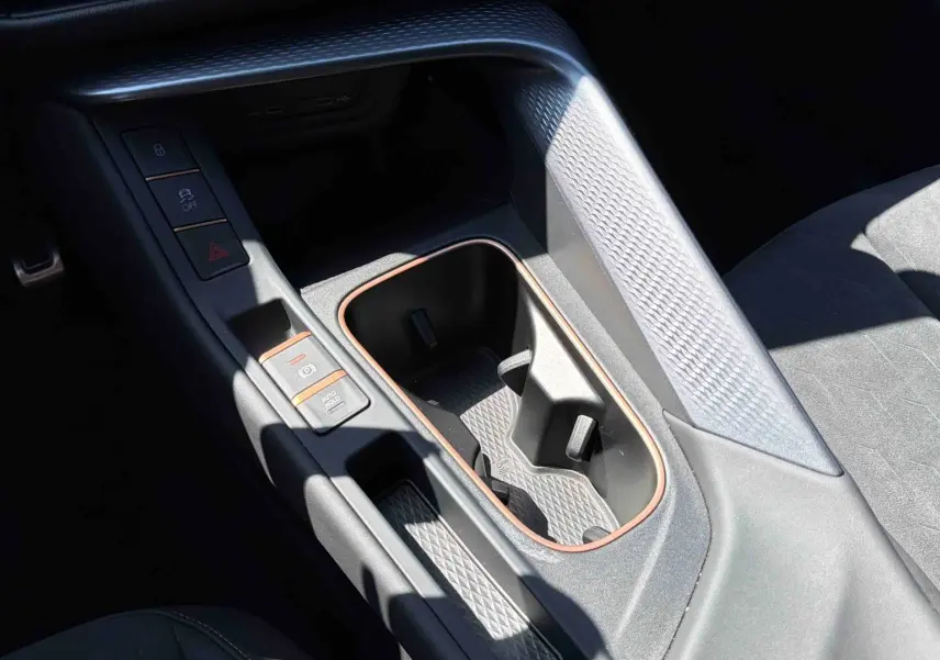Gros plan sur la console centrale intérieure de la CUPRA Terramar bleu, avec porte-gobelets et finitions cuivrées.