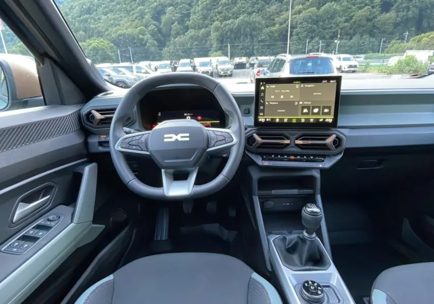 Intérieur du Dacia Bigster TCE 130 4x4 Extreme Plus 2025, vue du poste de conduite avec volant, écran tactile et levier de vitesses manuel.